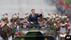 Presiden Perancis baru Emmanuel Macron di atas mobil militer di Champs Elysees menuju Arc de Triomphe di Paris, 14 Mei 2017. 