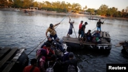 People belonging to a caravan of migrants from Honduras en route to the United States, cross the Suchiate river to Mexico from Tecun Uman, Guatemala, Jan. 18, 2019. 