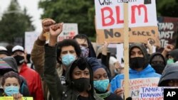 People raise their fists as they take part in a "Silent March" against racial inequality and police brutality that was organized by Black Lives Matter Seattle-King County, June 12, 2020, in Seattle.