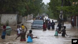 Warga Port-au-Prince, Haiti, mengarungi genangan banjir yang dipicu badai tropis Isaac. (Foto: AP/Dieu Nalio Chery)