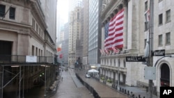 FILE - The normally busy area of Wall Street at the New York Stock Exchange is empty on a rainy day in New York, April 13, 2020. 