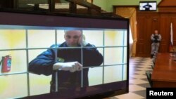 Pemimpin oposisi Rusia Alexei Navalny terlihat di layar melalui tautan video dari koloni pidana korektif IK-2 di Pokrov selama sidang pengadilan di Moskow, Rusia, 24 Mei 2022. (Foto: REUTERS/ Evgenia Novozhenina)