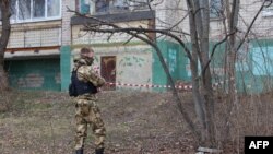 A self-defense unit volunteer tapes off an area near a damaged apartment building following a drone attack, in Belgorod, Russia, March 13, 2024.