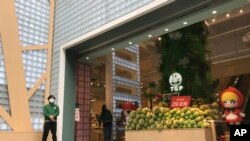 A store employee waits outside for customers at a re-opened retail street in Wuhan in central China's Hubei province on March 30, 2020. 