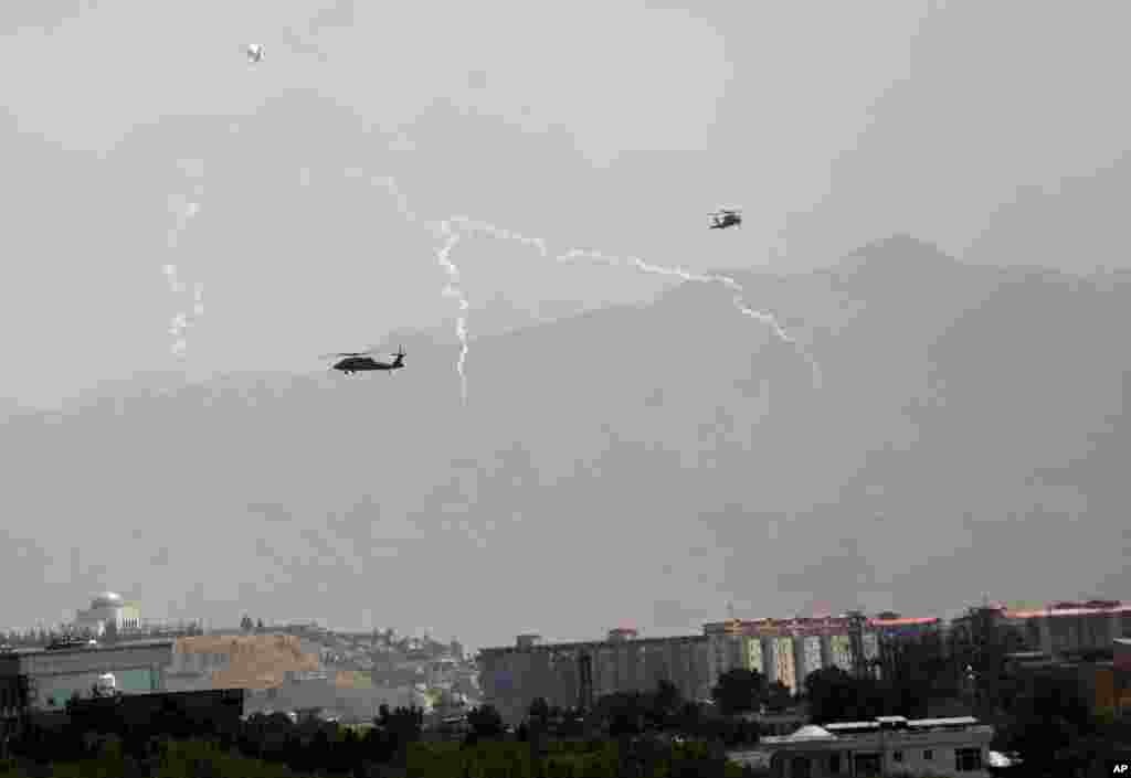 Anti-missile decoy flares are deployed as U.S. Black Hawk military helicopters and a dirigible balloon fly over the city of Kabul, Aug. 15, 2021.