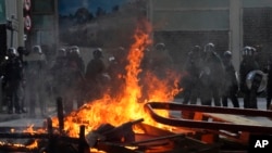 Police face a burning barricade during protests, Sept. 21, 2019, in Hong Kong. 