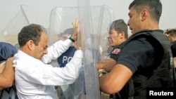 A parliamentarian from the pro-Kurdish Peoples' Democratic Party, Osman Baydemir (L), scuffles with riot police as he walks with his party members to the southeastern town of Cizre, near Idil in Sirnak province, Turkey, Sept. 10, 2015.