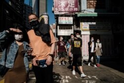 FILE - In this picture taken on on April 16, 2020 pedestrians wear face masks, as a precautionary measure against the COVID-19 coronavirus, in Hong Kong.