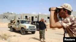 Un combattant des forces loyales au gouvernement d'union nationale de la Libye surveille les positions occupées par le groupe Etat islamique dans la zone d'Algharbiyat à Syrte, le 21 juin 2016.