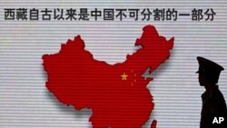 FILE - A security guard stands near an electronic screen featuring a map of China and Chinese characters that read, "Tibet has been an inalienable part of the Chinese territory since ancient times," in Beijing.
