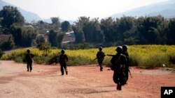 FILE - Myanmar army soldiers carrying weapons patrol on a road as part of operations against ethnic rebels, in Kokang, northeastern Shan State, more than 800 kilometers (500 miles) northeast of Yangon, Feb. 17, 2015.