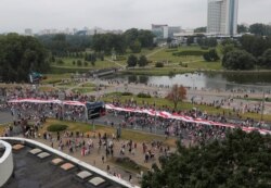 People carry a large historical white-red-white flag of Belarus during an opposition demonstration to protest against presidential election results, in Minsk, Belarus, Aug. 23, 2020.