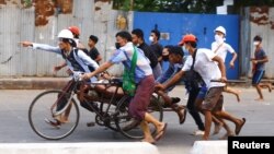 Des gens transportent une personne qui a été blessée lors d'une répression des forces de sécurité contre des manifestants anti-coup d'État à Thingangyun, Yangon, Birmanie, le 14 mars 2021.