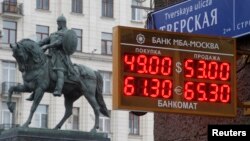 A board showing currency exchange rates, in front of a monument to Prince Yury Dolgoruky, who founded Moscow in 1147, in the capital Moscow, Dec. 1, 2014.