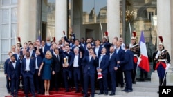 French President Emmanuel Macron, next to his wife Brigitte sing with the French soccer players at the presidential Elysee Palace after the parade down the Champs-Elysees, July 16, 2018. 