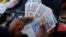 A cashier in a leading supermarket dispenses the new $10 ZiG, short for Zimbabwe Gold, note from a till as change in Harare on April 30, 2024.