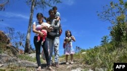 FILE - Venezuelan police officer Cesar Marcano (C) along with his family seek refuge in Brazil, at the Brazil-Venezuela border, in Pacaraima February 2019. (Photo by Nelson Almeida / AFP) 