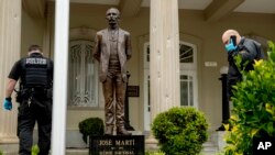  30일 미국 주재 쿠바 대사관에서 경찰들이 총격을 받아 훼손된 건물 외벽 사이로 현장조사를 하고 있다. 경찰은 이번 사건 용의자인 알렉산더 알라조(42)를 체포했고 인명 피해는 없었다고 전했다. 