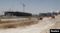 FILE - Construction cranes and bulldozers operate in Doha, June 25, 2013.