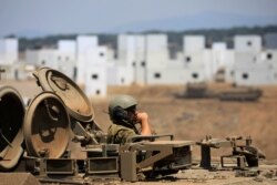 An Israeli soldier rides an armored personnel carrier (APC) as it maneuvers during in a drill at an urban warfare training base in the Israeli-controlled Golan Heights near the Israel-Syria border, Aug. 4, 2020.