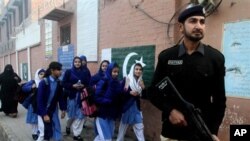 A Pakistani police officer stands guard as children make their way to school in Lahore, Pakistan, Monday. Pakistani authorities closed schools last week, in the country's largest province, Punjab, following warnings of possible militant attacks. The U.S. will give Pakistan over $800 million in foreign aid in 2016. (AP Photo/K.M. Chaudary)