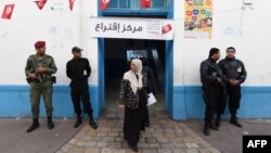 Tunisian security officers stand guard outside at a polling station in the center of Tunis on Nov. 23, 2014, during Tunisia's first presidential election since the 2011 revolution. 