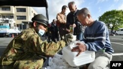 Earthquake-affected evacuees receive rice rations from Japanese Self-Defense Forces personnel at the Mashiki village office in Kumamoto prefecture, April 17, 2016. Rescuers were racing against the weather to try to find trapped survivors.