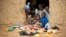 FILE - Refugees sit at the door of their home at the Minawao Refugee Camp in northern Cameroon.