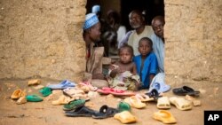 FILE - Refugees sit at the door of their home at the Minawao Refugee Camp in northern Cameroon on April 18, 2016. (AP Photo/Andrew Harnik)
