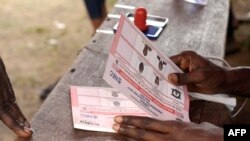 Un membre de la commission électorale nationale prépare les bulletins de vote lors du second tour des élections présidentielles à Monrovia, Liberia, 26 décembre 2017. / AFP PHOTO / SEYLLOU