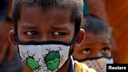 Children wearing protective masks wait to enter the Lokmanya Tilak Terminus railway station, amidst the spread of the COVID-19 in Mumbai, India, April 14, 2021. 
