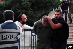 FILE - A civilian, second left, spits at a member of Turkey armed forces as he is escorted by police with a group of others for their suspected involvement in the attempted coup in Turkey, July 17, 2016.