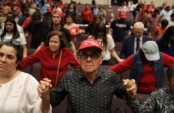 FILE - People pray together during the 'Evangelicals for Trump' campaign event held at the King Jesus International Ministry as they await the arrival of President Donald Trump on Jan. 3, 2020 in Miami, Florida.