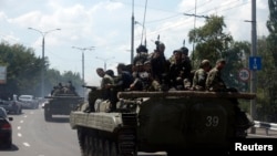 Pro-Russian separatist fighters on armored vehicles in the eastern Ukrainian city of Donetsk, July 10, 2014.
