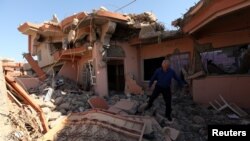 FILE - A Christian man inspects his neighbors' home, destroyed by Islamic State militants in the Christian city of Qaraqosh, Iraq, Sept. 12, 2018.