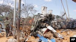 Seorang tentara berjaga di dekat puing-puing kendaraan di Mogadishu setelah terjadi bom mobil di Mogadishu, Somalia, Sabtu, 28 Desember 2019. (Foto: AP)