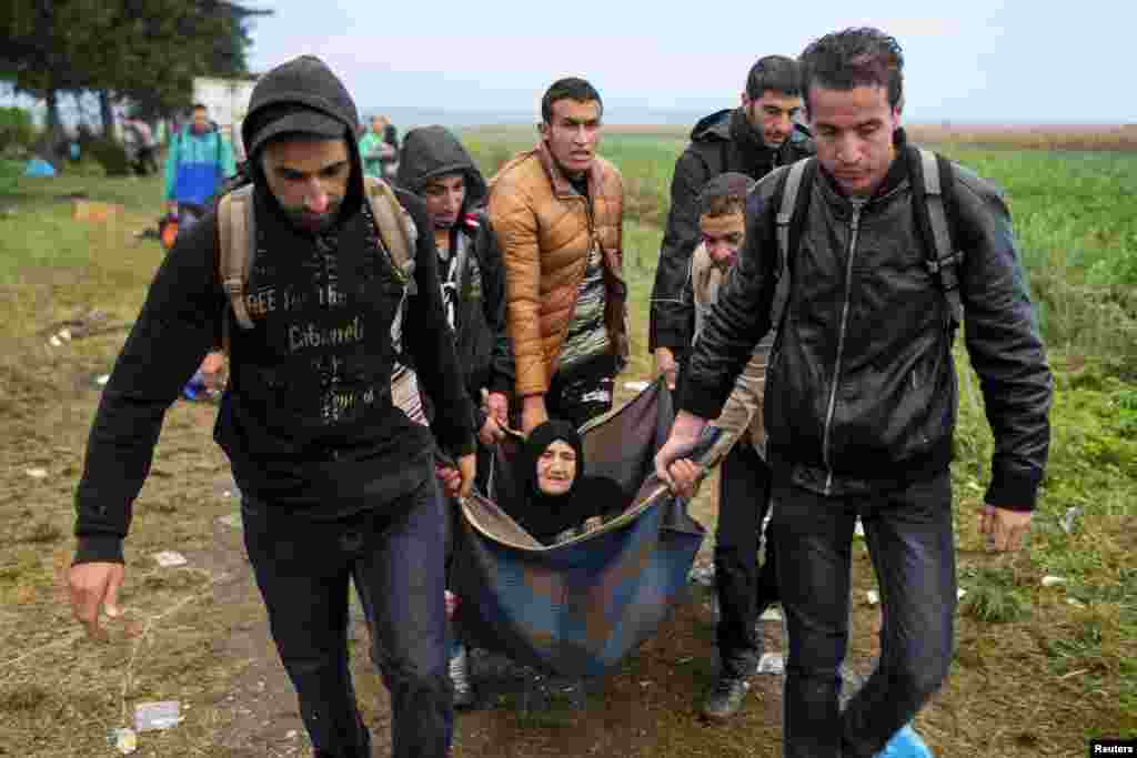 Migrants carry an elderly woman as they walk on a field, after they crossed the border with Serbia, near Tovarnik, Croatia. European Union leaders could promise billions of euros in new funding for Syrian refugees at an emergency summit where they will also try to patch up bitter divisions over the migration crisis.