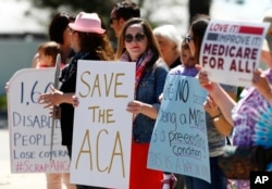 Larissa Pisney, center, of Denver joins a line of people during a protest outside the Aurora, Colo., office of Republican U.S. Rep. Mike Coffman over the health care overhaul bill that was voted on in the U.S. House, May 4, 2017.