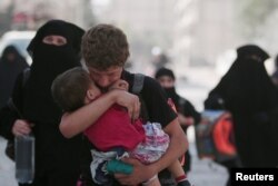 A civilian carries a child as he walks with others after they were evacuated by the Syria Democratic Forces (SDF) fighters from an Islamic State-controlled neighborhood of Manbij, in Aleppo Governate, Syria, August 12, 2016.