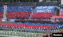 People gather at a stadium during celebrations marking the fourth anniversary of Donetsk's self-declared independence in Donetsk, Ukraine, May 11, 2018. The banner reads: "Russia - DNR together!" DNR is the initialism for the Donetsk People's Republic.