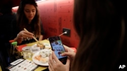 ນາງຊີອາຣາ ວາເລັນຊາໂນ (ຂວາ), ຖ່າຍຮູບອາຫານຂອງລາວ ໃນຂະນະທີ່ລາວມາກິນເຂົ້າສວາຍກັບເພື່ອນຂອງລາວ ກິວເລຍ ເຕີຣາໂນວາ ຢູ່ທີ່ຮ້ານ 'ນີ້ບໍ່ແມ່ນຊູຊິບາ,' ໃນເມືອງມີລານ, ປະເທດອີຕາລີ, ວັນທີ 18 ຕຸລາ 2018.