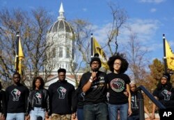 FILE - Jonathan Butler, front left, addresses a crowd following the announcement that University of Missouri System President Tim Wolfe would resign Nov. 9, 2015, at the university in Columbia, Mo.