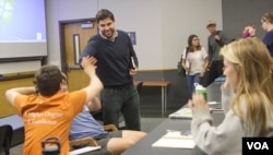 Carlos Galdeano (standing) high fives a student