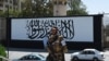 FILE - A member of the Taliban's Fateh, a special forces unit, stands guard outside the U.S. embassy in Afghanistan, now with a Taliban flag painted on its outer concrete wall, in Kabul, Sept. 8, 2021. 