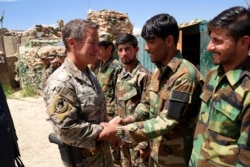 FILE - Gen. Scott Miller, commander of U.S. and NATO forces in Afghanistan shakes hands with Afghan National Army soldiers during a visit at a checkpoint in Nerkh district of Wardak province in west Kabul, June 6, 2019.