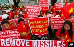 Demonstrators display placards during a rally at the Chinese Consulate to protest Beijing's militarization of disputed islands in the South China Sea, in Manila, Philippines, Feb. 25, 2016.