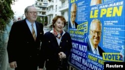 ARCHIVES - Le leader du Front national, Jean Marie Le Pen, passe devant des affiches électorales alors qu'il marche avec son adjoint près d'un bureau de vote, le 21 mars 1993