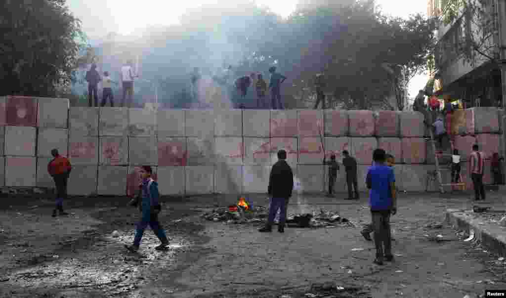 Youths climb a wall that was built by police to prevent clashes between protesters and police at Tahrir Square, Cairo, Egypt, November 29, 2012.