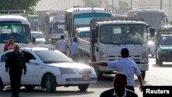 A worker directs vehicles queuing in line at a petrol station, Cairo, March 12, 2013.