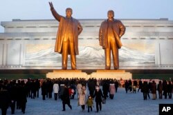 Warga mengunjungi patung perunggu mendiang pemimpin mereka Kim Il Sung, kiri, dan Kim Jong Il di Bukit Mansu di Pyongyang, Korea Utara Kamis, 16 Desember 2021, dalam rangka peringatan 10 tahun kematian Kim Jong Il. (Foto: AP)